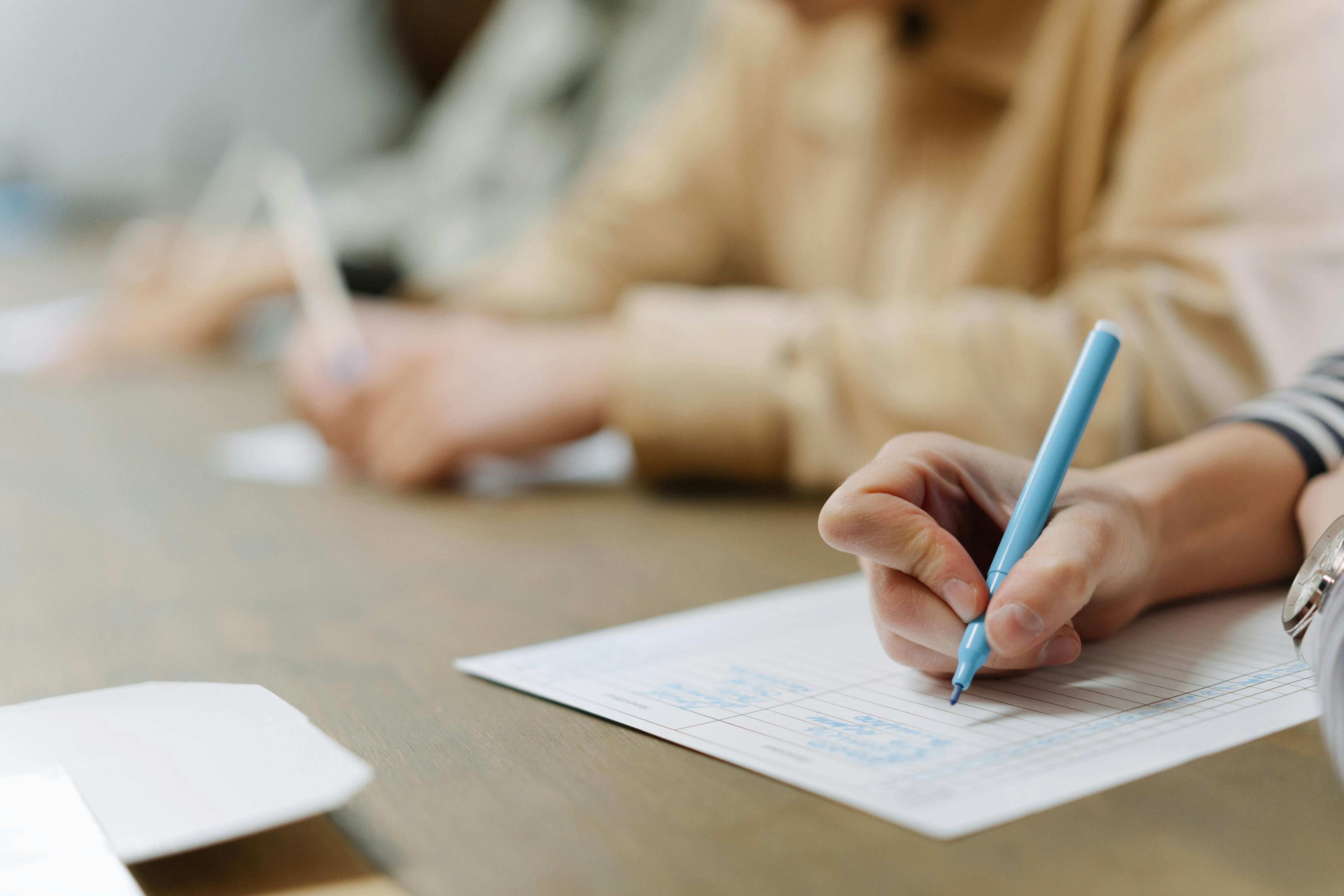 personne écrivant sur une feuille